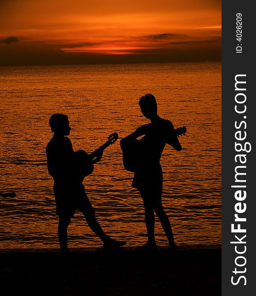 Some boys playing guitar at the beach during sunset. Some boys playing guitar at the beach during sunset