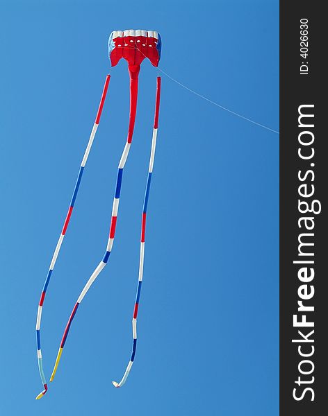 Red, white and blue kite on a blue sky background