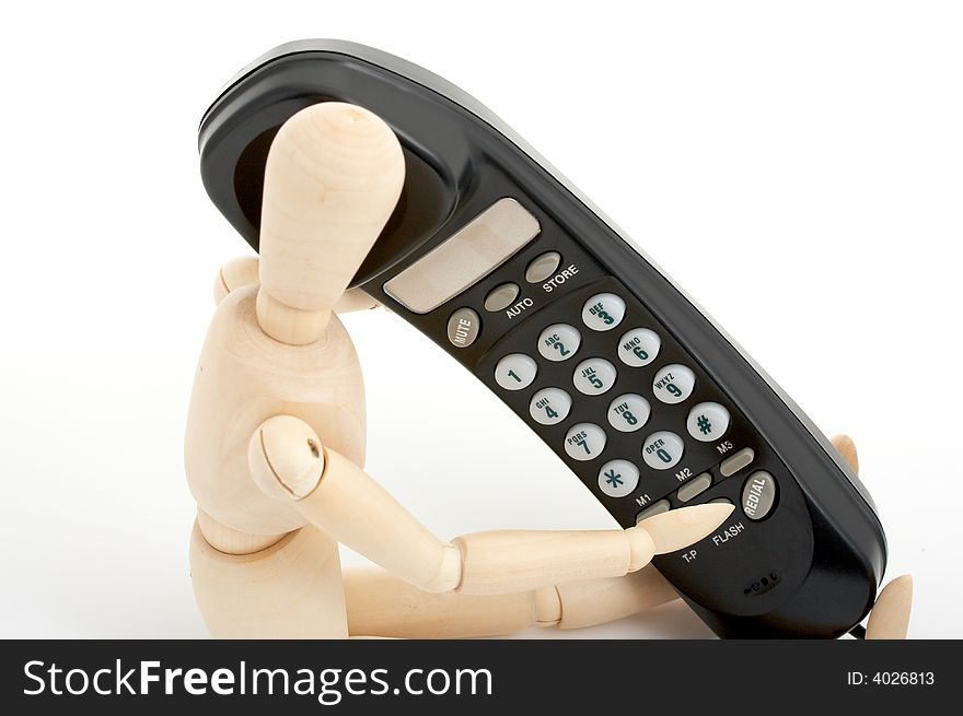 Wooden figure holding a black telephone over a white background