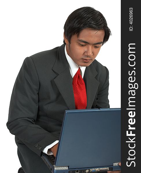 A man sitting while working on his laptop computer