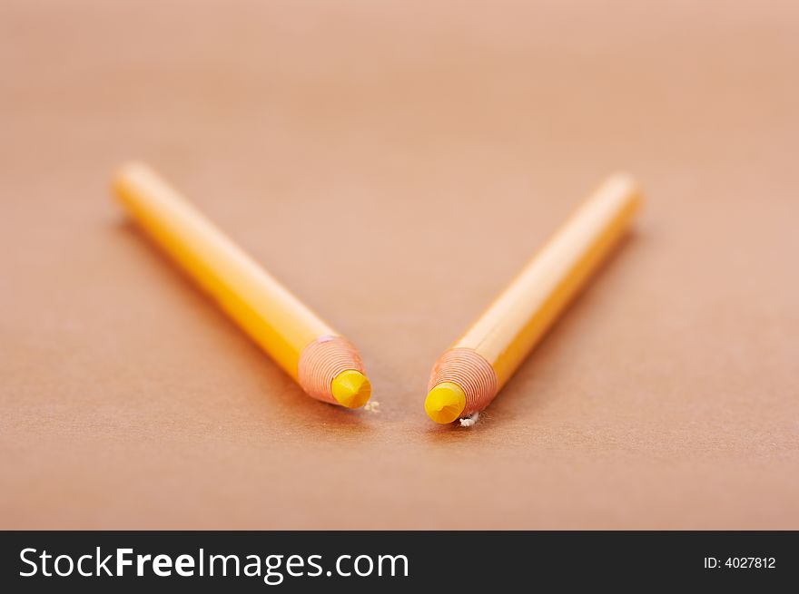 Two yellow pencil on a brown paper