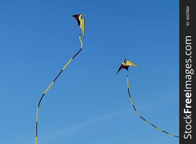 Two colourful stunt-kites flying on a blue sky background. Two colourful stunt-kites flying on a blue sky background