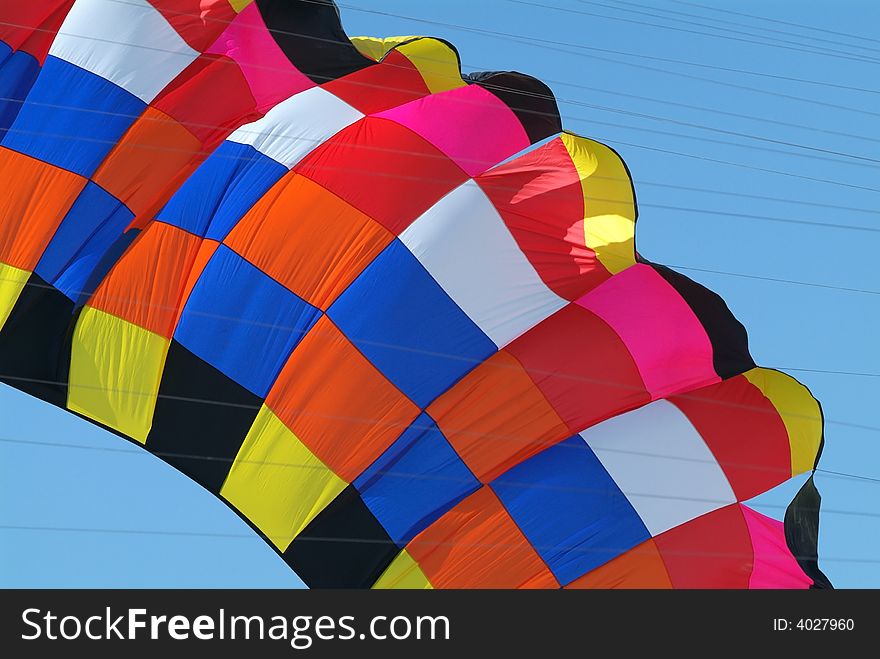 Detail of very large kite in various colours. Kite lines visible. Detail of very large kite in various colours. Kite lines visible.