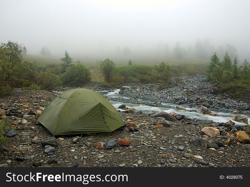 Morning camp and fog near mountain river