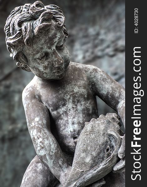 Statue of boy looking at seashell