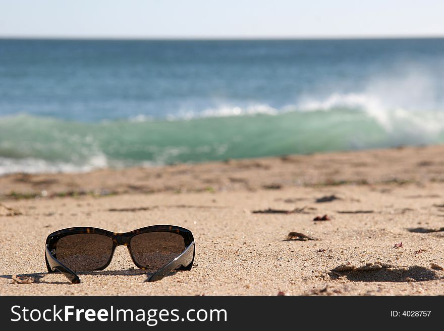 A pair of sunglasses by the sea. A pair of sunglasses by the sea