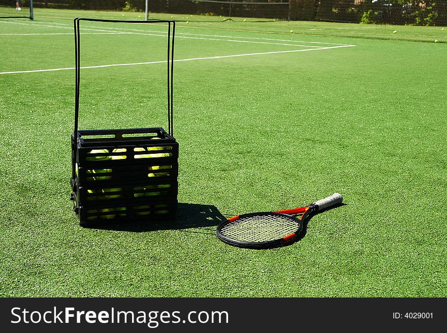 Tennis racket and tennis balls in crate on a court. Tennis racket and tennis balls in crate on a court