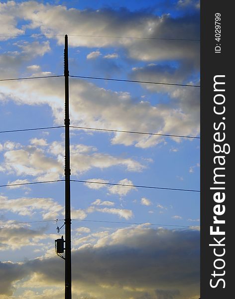 Transformer and power lines are held in place by pole and magnificent cloudscape at sunset. Transformer and power lines are held in place by pole and magnificent cloudscape at sunset.