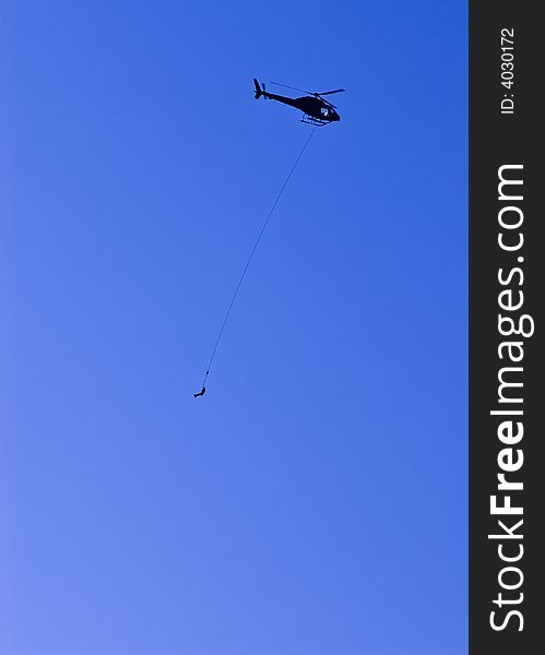 A helicopter air lifts an injured person on a long line beneath the aircraft in a dramatic rescue high in the mountains. A helicopter air lifts an injured person on a long line beneath the aircraft in a dramatic rescue high in the mountains.