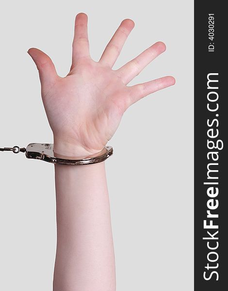 Picture of a female arm with handcuffs on gray background. Picture of a female arm with handcuffs on gray background.