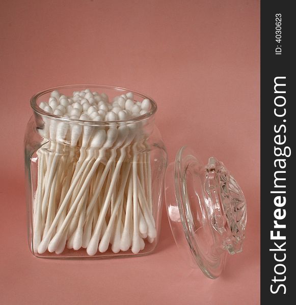 Cotton swabs in a jar on a pink background