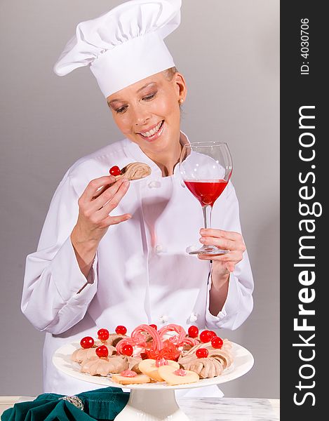 Passive posed smiling female Chef enjoying a cookie from and elegant cherry dessert plate. Passive posed smiling female Chef enjoying a cookie from and elegant cherry dessert plate.