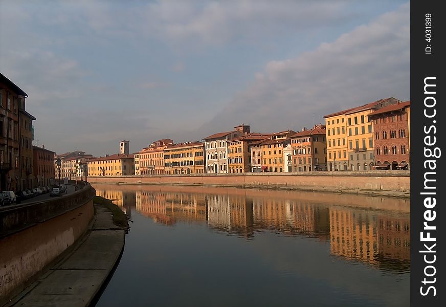 Buildings and their reflections along the bend in an italian waterway.