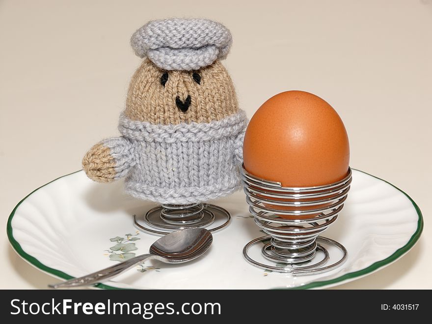 Soft boiled egg on plate with spoon, with woollen coddled second egg. Soft boiled egg on plate with spoon, with woollen coddled second egg