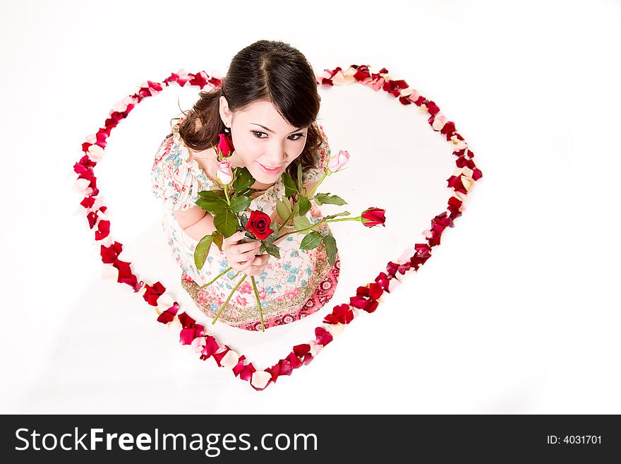 Young woman with roses sitting inside a rose petal heart shape. Young woman with roses sitting inside a rose petal heart shape