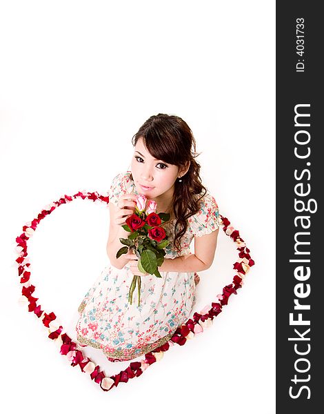 Young woman with roses sitting inside a rose petal heart shape. Young woman with roses sitting inside a rose petal heart shape