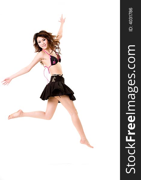 Young woman in bikini top & skirt jumping freely and happily. Young woman in bikini top & skirt jumping freely and happily