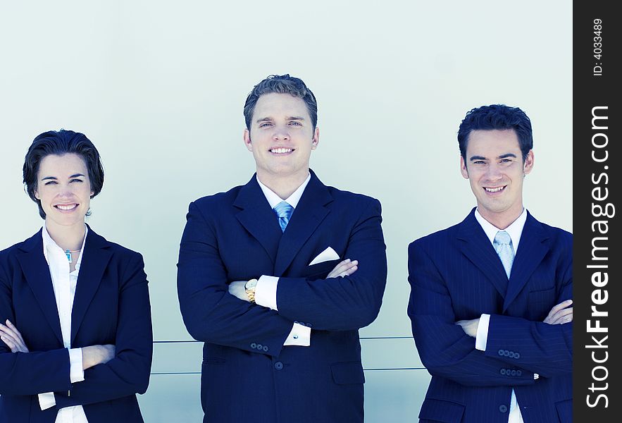 Three business people standing in a row looking at camera. Three business people standing in a row looking at camera.