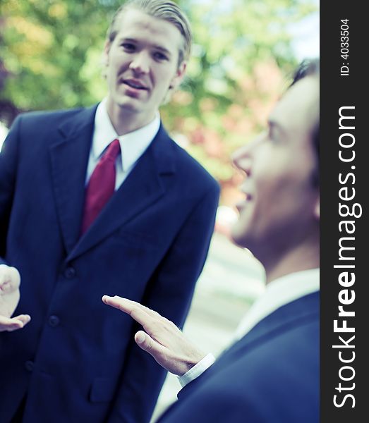 Two businessmen standing talking outdoors. Two businessmen standing talking outdoors