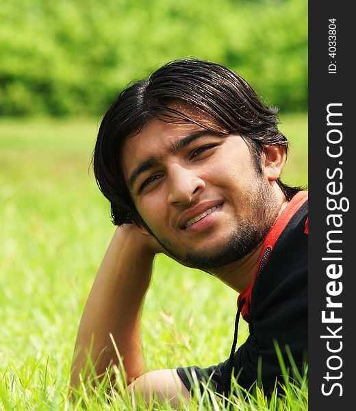 An attractive Asian boy with happy facial expression resting on the grass outdoors. An attractive Asian boy with happy facial expression resting on the grass outdoors.