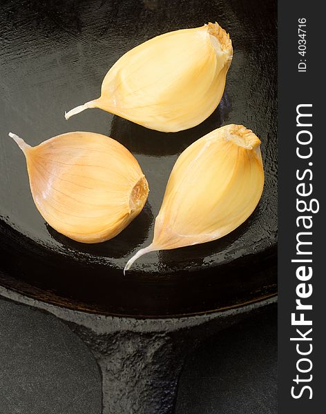 Cloves of garlic in a cast iron skillet.