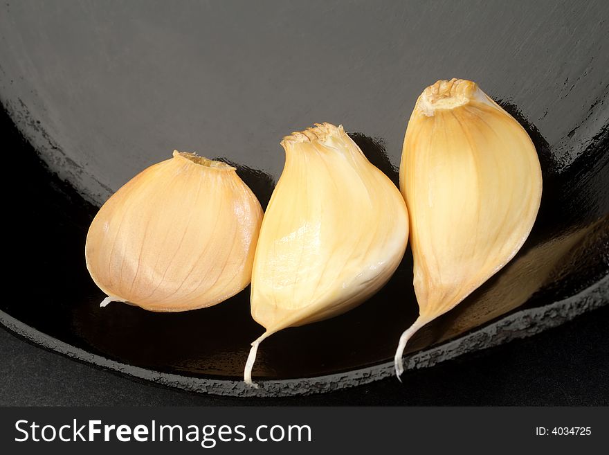 Three Cloves of garlic in a cast iron skillet.