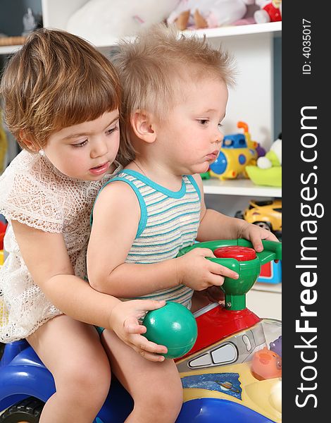 Two children in the playroom on toy scooter