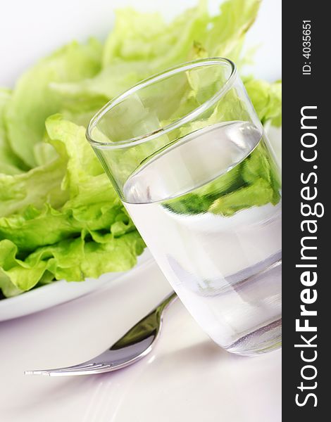 Fresh green salad with a glass of water and a fork. Fresh green salad with a glass of water and a fork