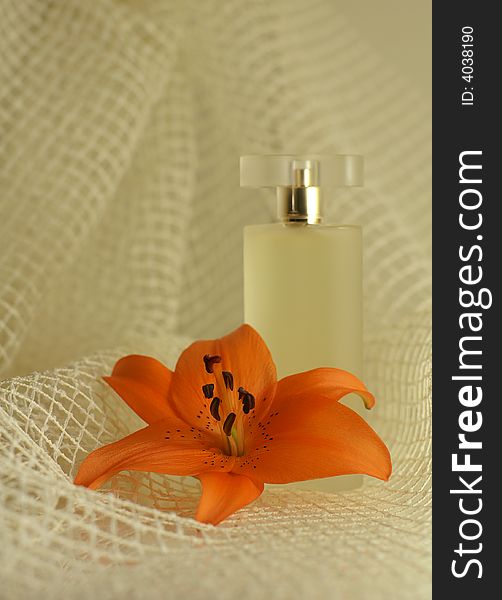 Perfume with an orange lily on the blury soft background