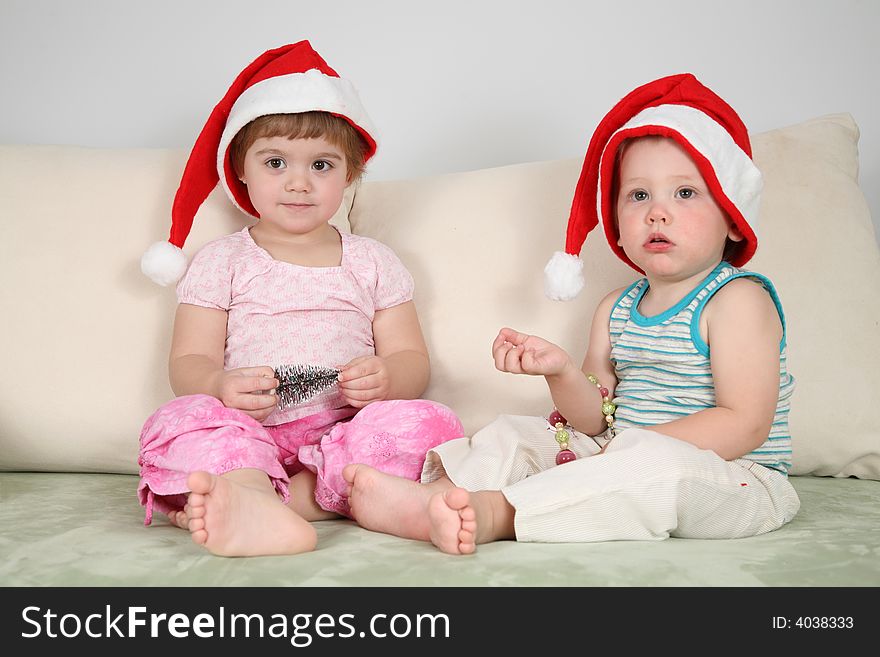 Two children on sofa in santa claus hats. Two children on sofa in santa claus hats