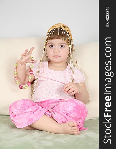 Girl on  sofa in  eastern hat with beads. Girl on  sofa in  eastern hat with beads