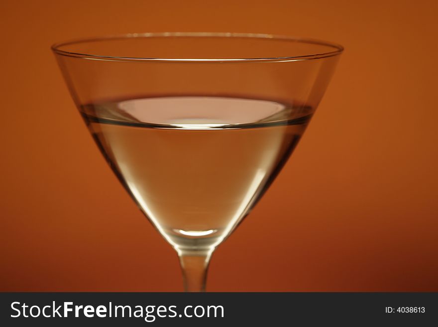 Cocktail glass with water on orange background