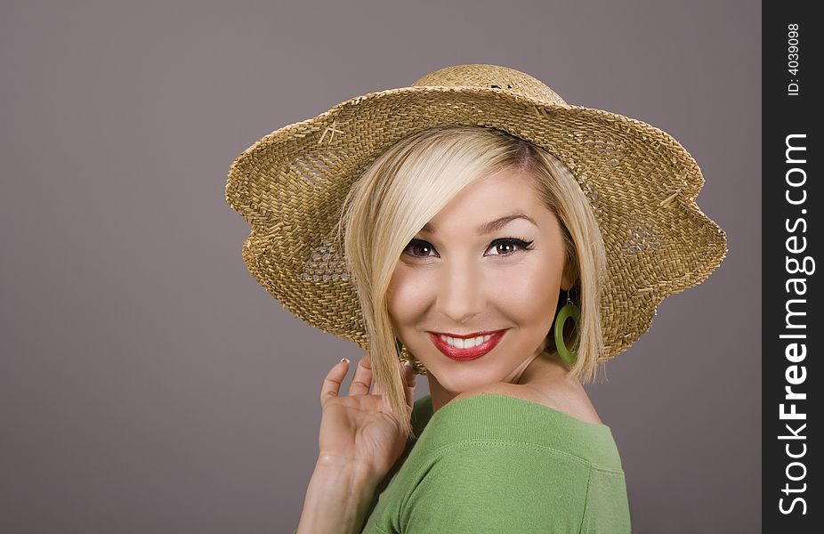 A blonde model in a green blouse and a straw hat smiling at the camera. A blonde model in a green blouse and a straw hat smiling at the camera