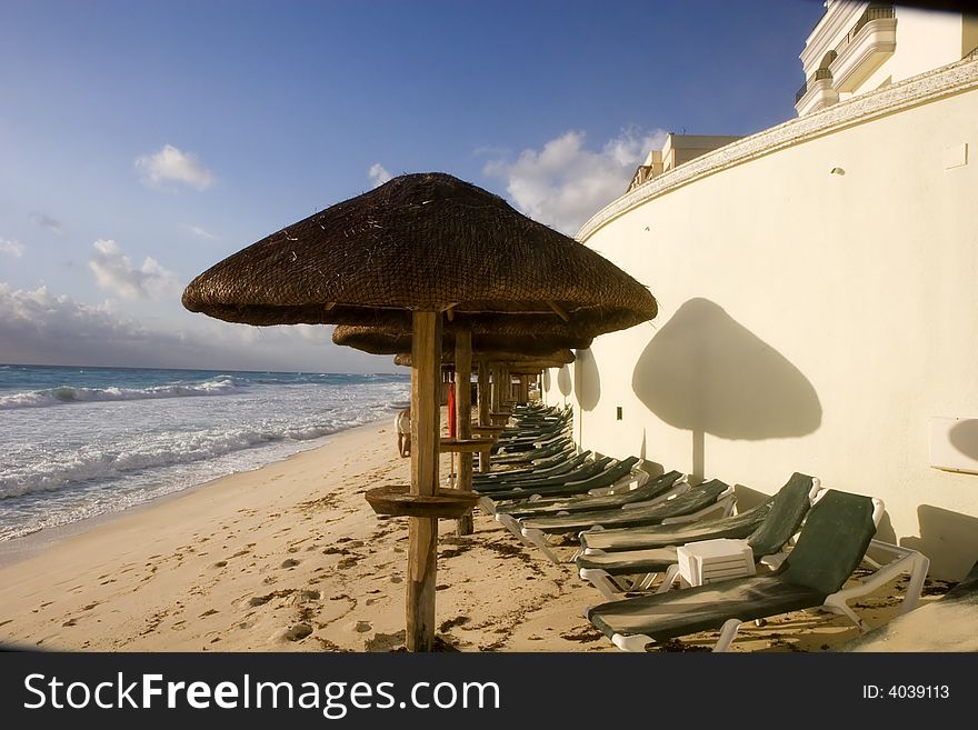 A column of umbrellas over a row of chaise lounges on the beach. A column of umbrellas over a row of chaise lounges on the beach