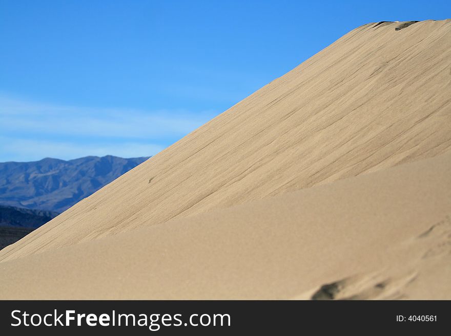 Sloping sand dune in a hot dry desert with mountains in the background. Sloping sand dune in a hot dry desert with mountains in the background