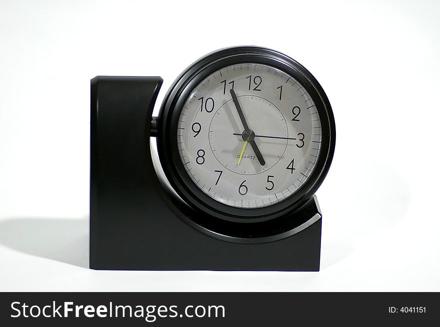 Black alarm clock stands against the white background