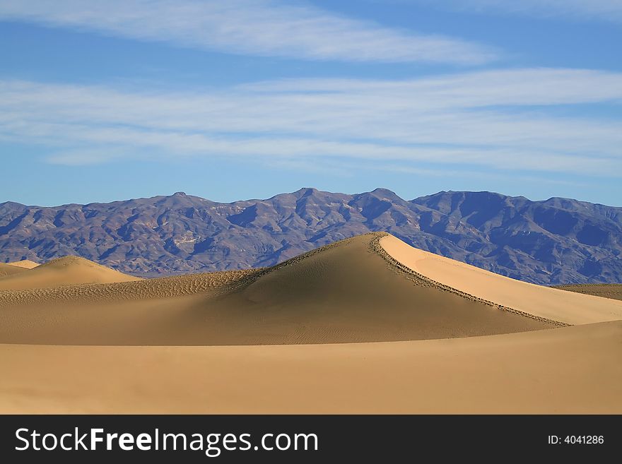 Dry desert sand dunes with mountains in the background. Dry desert sand dunes with mountains in the background