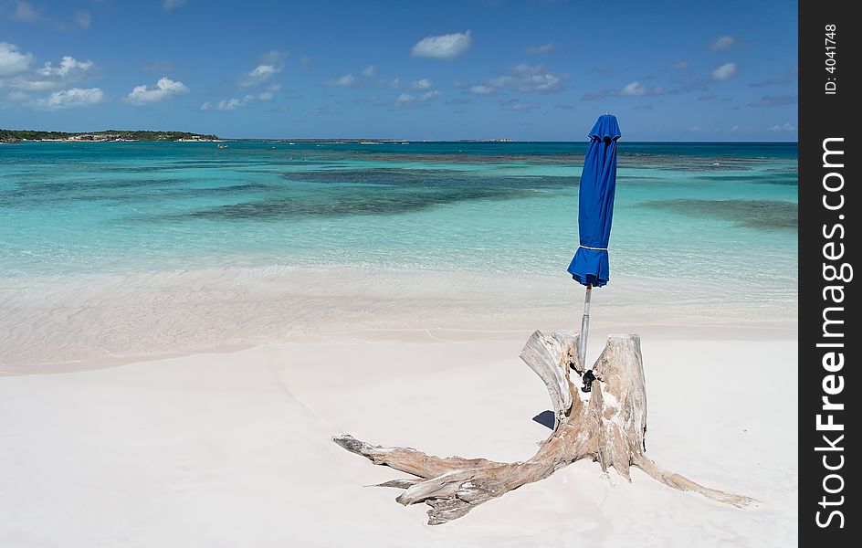 Beautiful white caribbean beach with blue umbrella and a stranded root. Beautiful white caribbean beach with blue umbrella and a stranded root