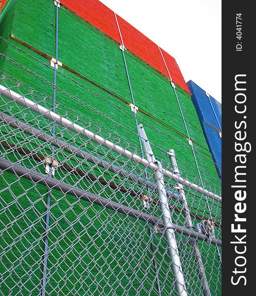 Green, red and blue stacks of lumber behind a wire fence. Green, red and blue stacks of lumber behind a wire fence