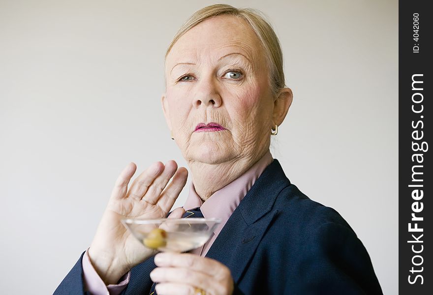 Dramatic senior woman in a man's suit holding a Martini. Dramatic senior woman in a man's suit holding a Martini.