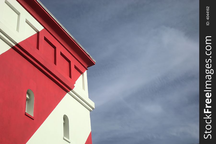 Part of a colourful red and white lighthouse on the shore. Part of a colourful red and white lighthouse on the shore