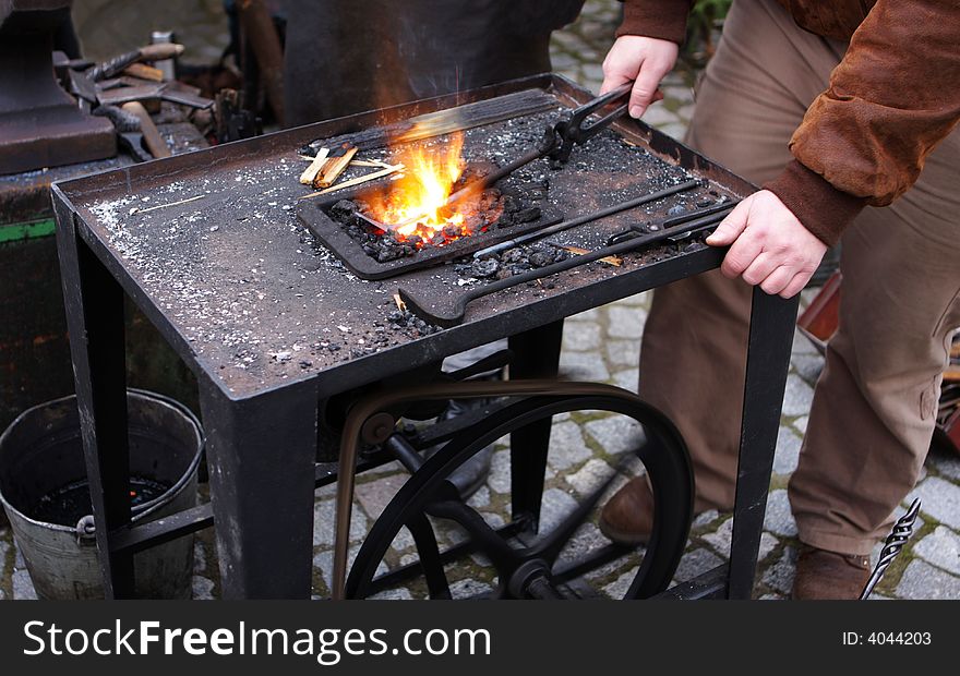 Smith standing beside smith´s forge with fire and smith´s tools. Smith standing beside smith´s forge with fire and smith´s tools