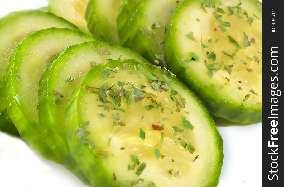 Cucumber slices with herbs over white background