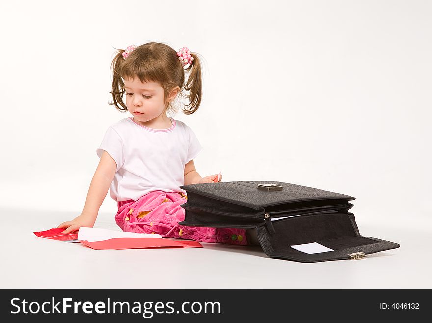 Cute little girl arranging papers in a briefcase. Cute little girl arranging papers in a briefcase