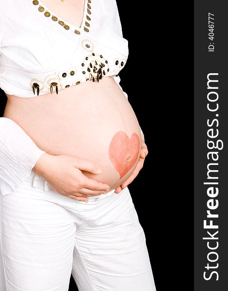 Red heart on a pregnant tummy with a black background