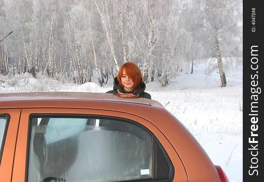 Red-haired girl and orange car at winter day