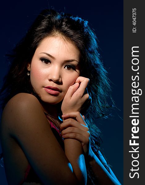 Young woman with a moody sensual alluring look under blue lighting