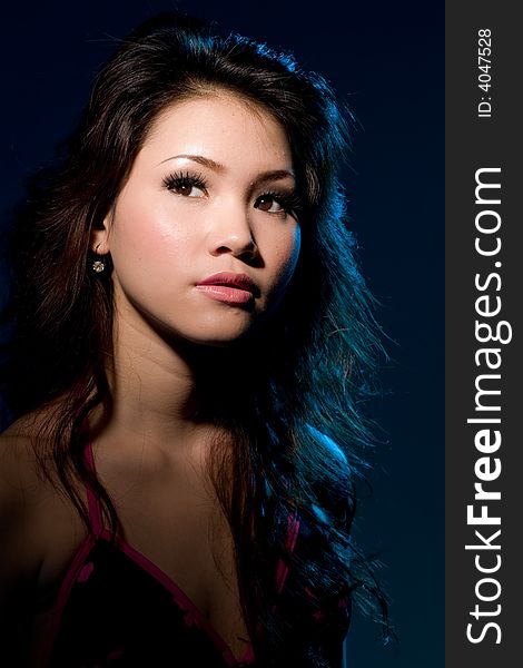 Young woman with a moody sensual alluring look under blue lighting