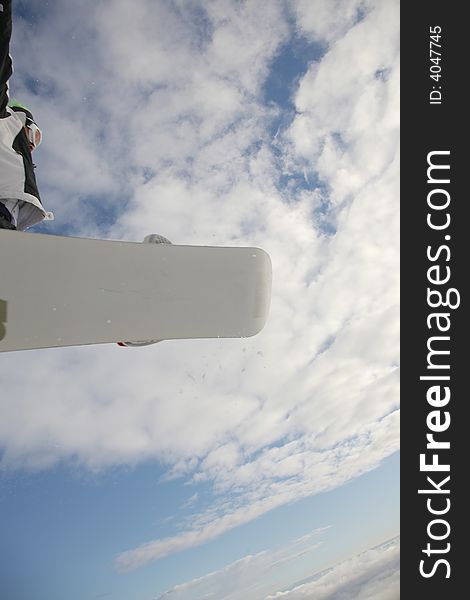 Snowboarder launching off a jump; vertical orientation, afternoon light.