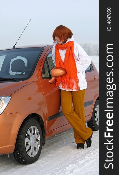 Red-haired girl and orange car on winter road